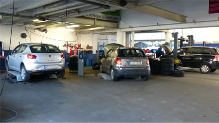 Werkstatthalle von Auto Wittmann mit mehreren Fahrzeugen auf Hebebühnen und an Arbeitsplätzen